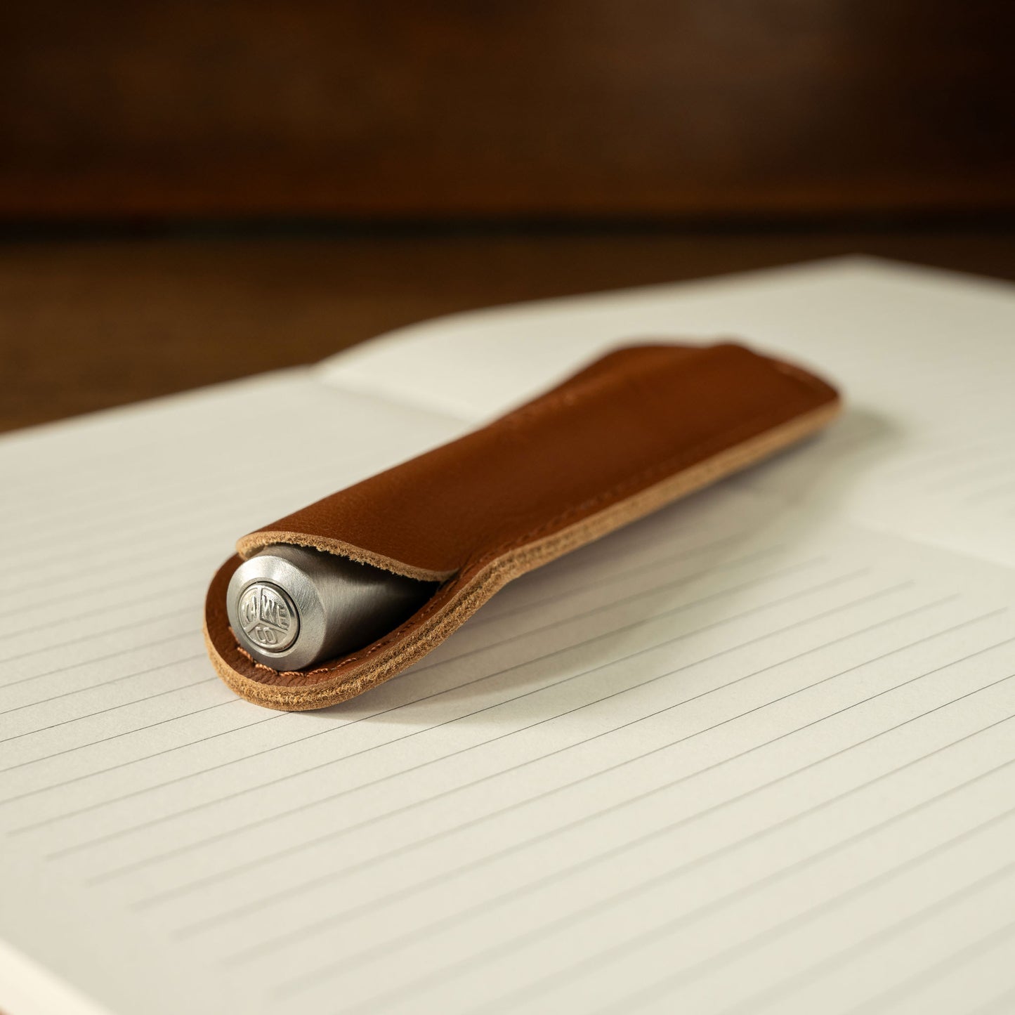 Kaweco brandy leather pen pouch with a silver pen inside on lined paper