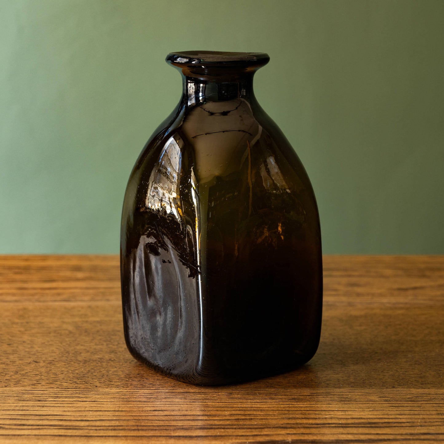 Side profile of La Soufflerie Bouteille Carre Petit. A beautiful and versatile dark brown free blown glass bottle.  