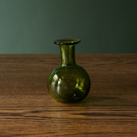 La Soufflerie small green glass bud vase on a wooden surface 