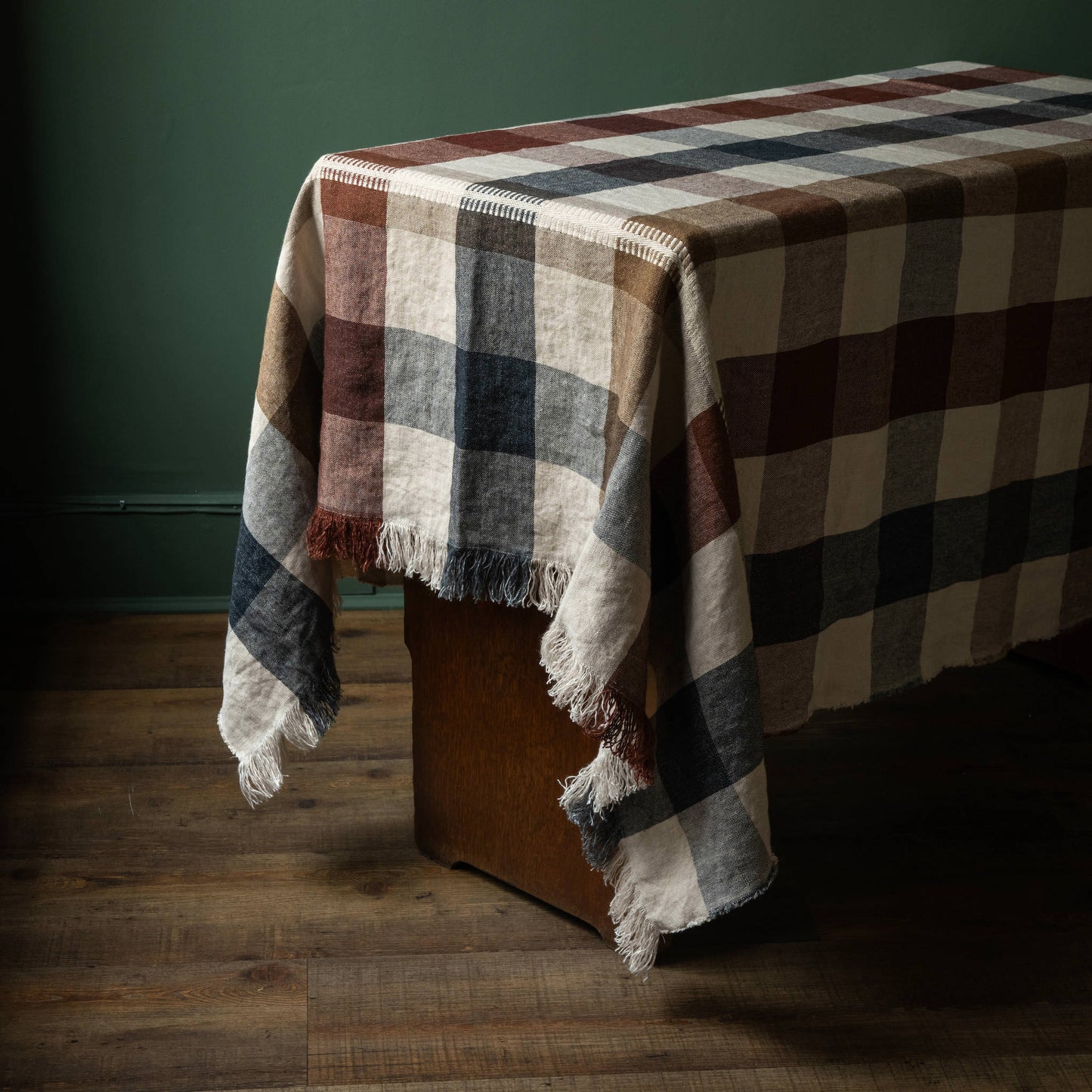 Libeco Maxine table throw, featuring a checked design on a natural base with tones of burgundy, grey/blue and browns with fringed edges