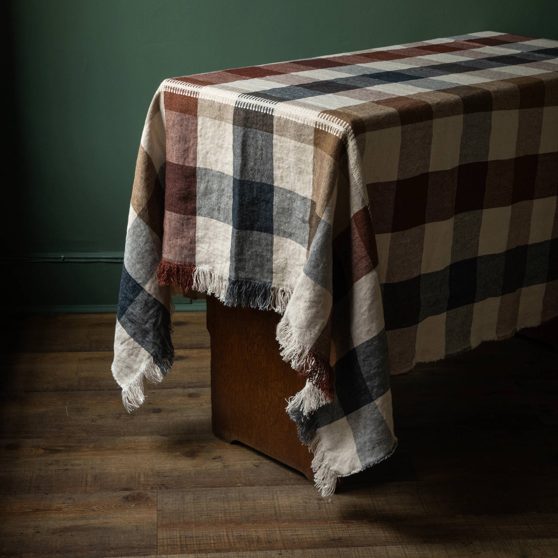 Libeco Maxine table throw, featuring a checked design on a natural base with tones of burgundy, grey/blue and browns with fringed edges
