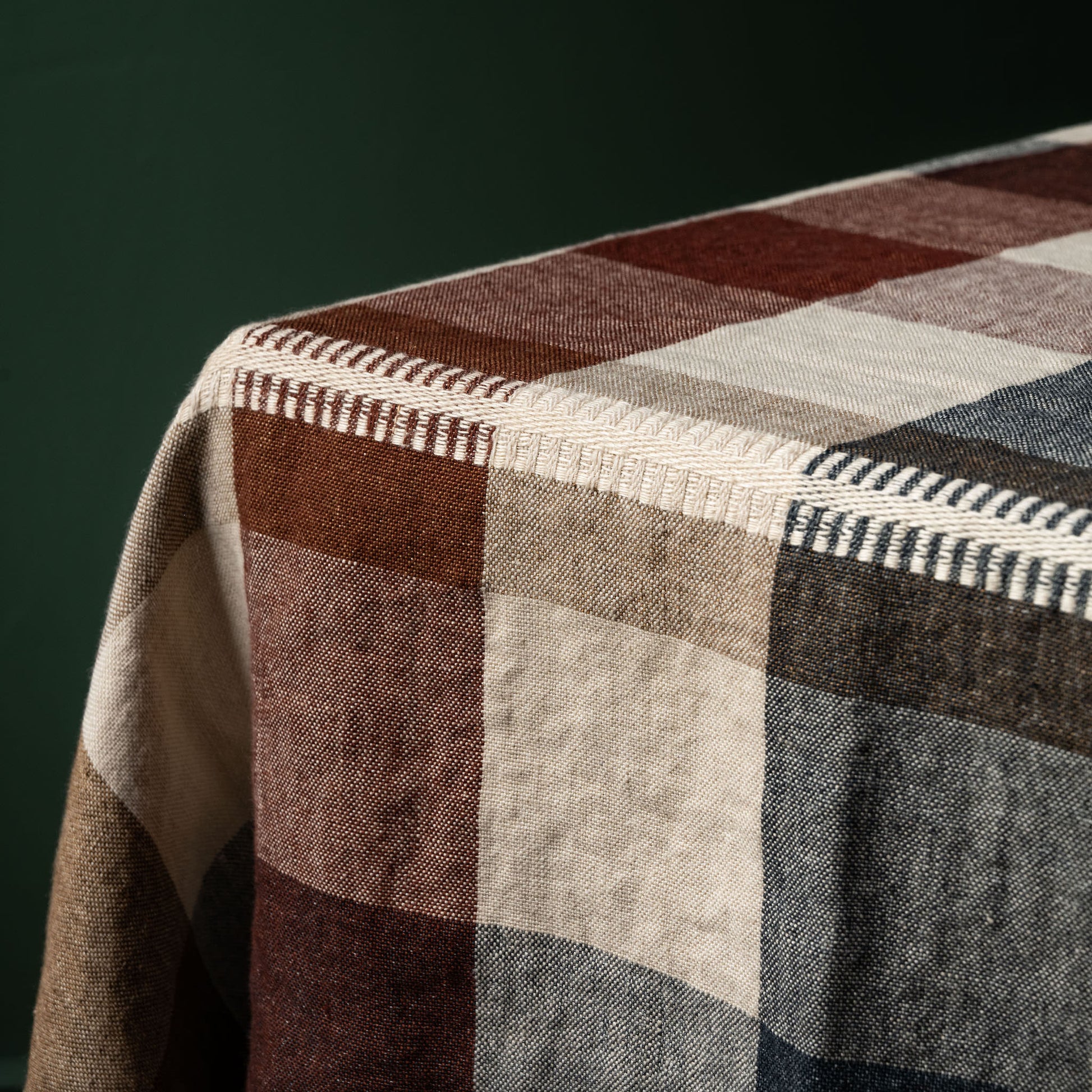 Close up of Libeco Linen Maxine checkered table throw with brown, beige, and blue pattern on a dark background