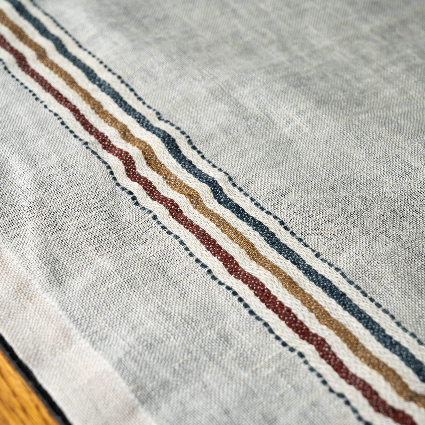 Close-up of Libeco Perry linen off-white napkin with a striped border featuring red, blue, and dusty brown stripes.
