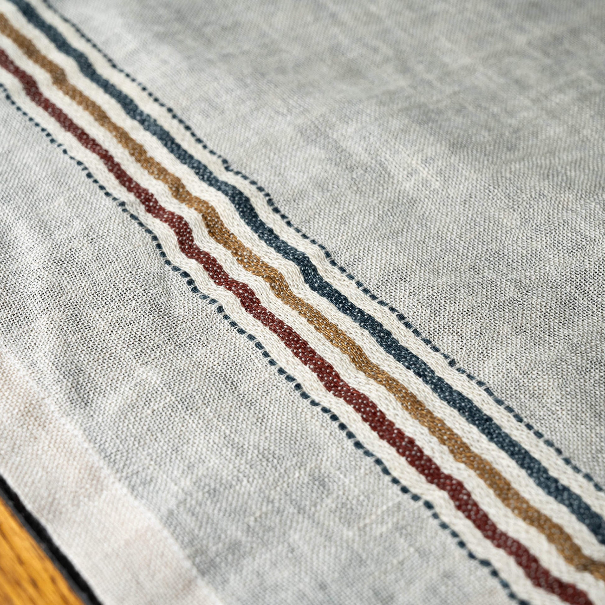 Close-up of Libeco Perry linen off-white napkin with a striped border featuring red, blue, and dusty brown stripes.