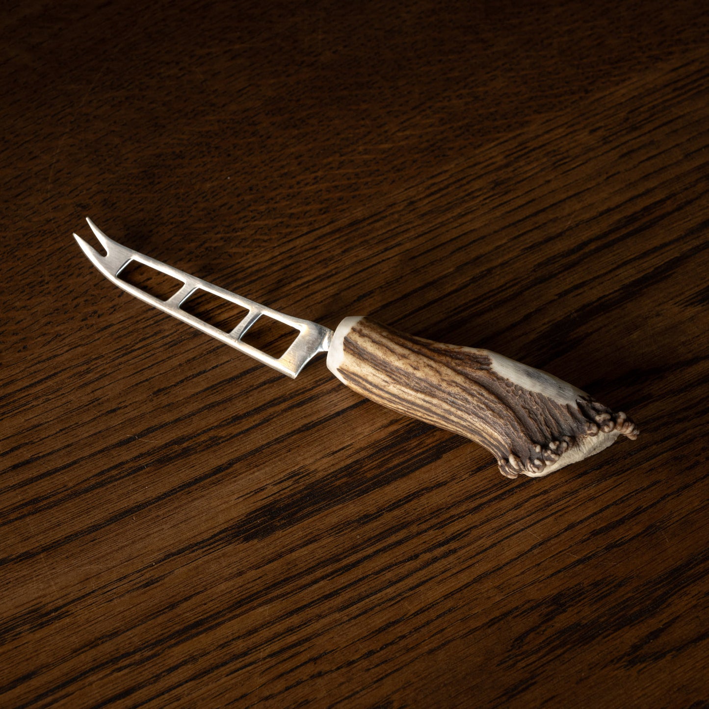 Soft cheese knife with antler handle on a wooden surface