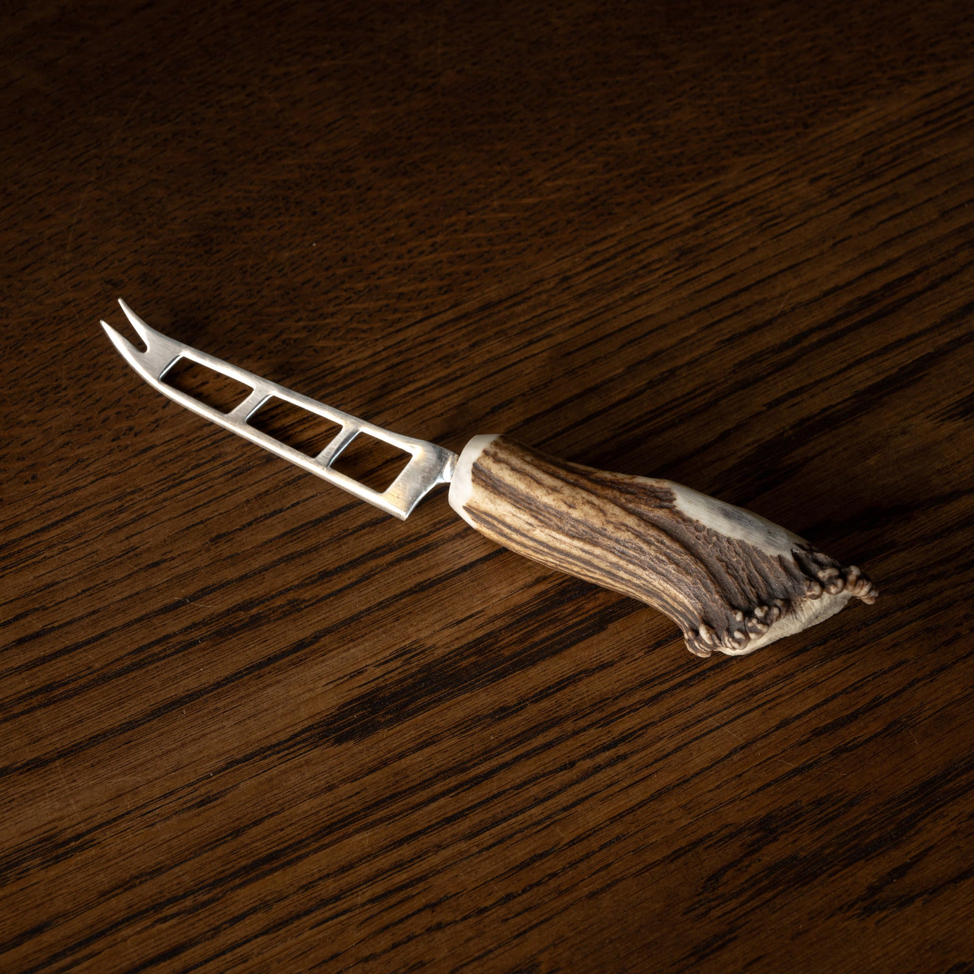 Soft cheese knife with antler handle on a wooden surface