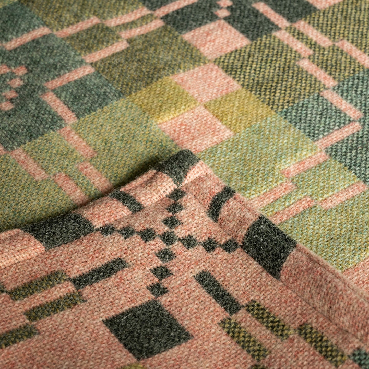 Close up of Melin Tregwnt Welsh wool blanket. Vintage Star design in hues of pink and green 