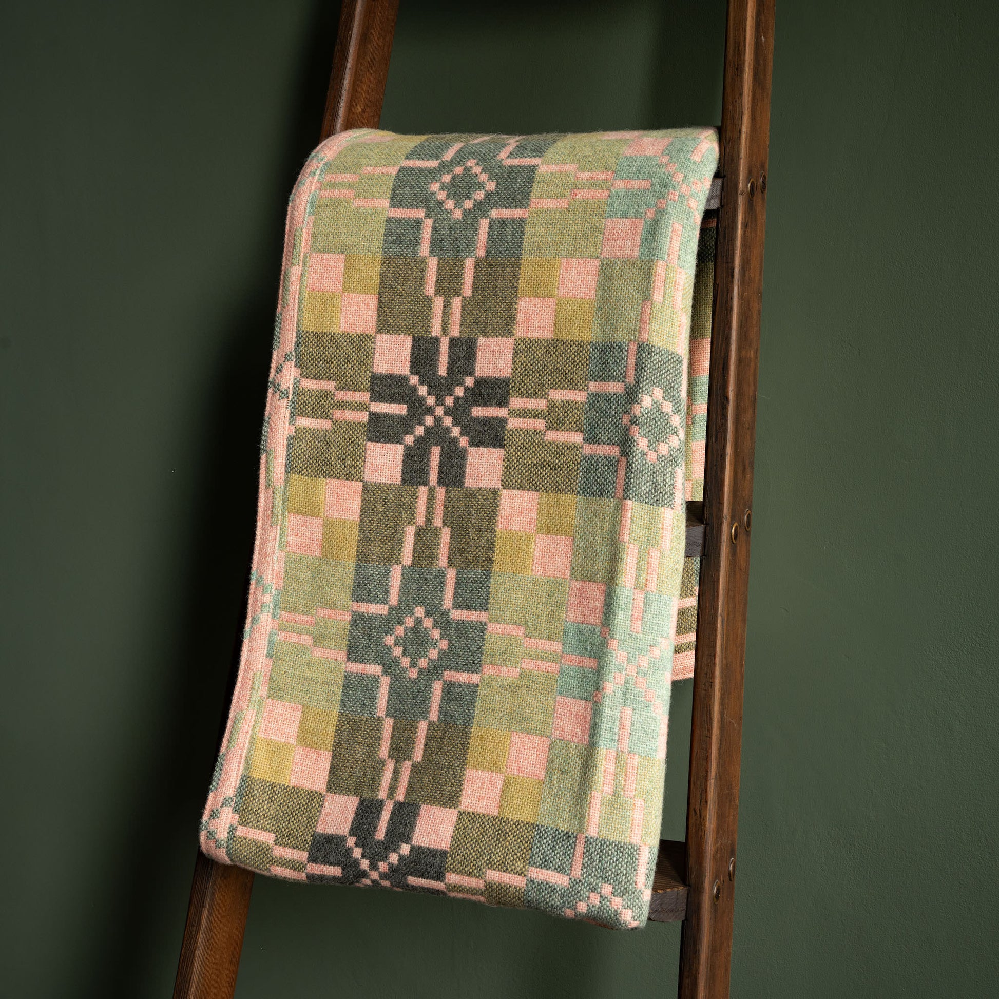 Reverse side of Melin Tregwnt Welsh wool blanket. Vintage Star design in hues of pink and green 