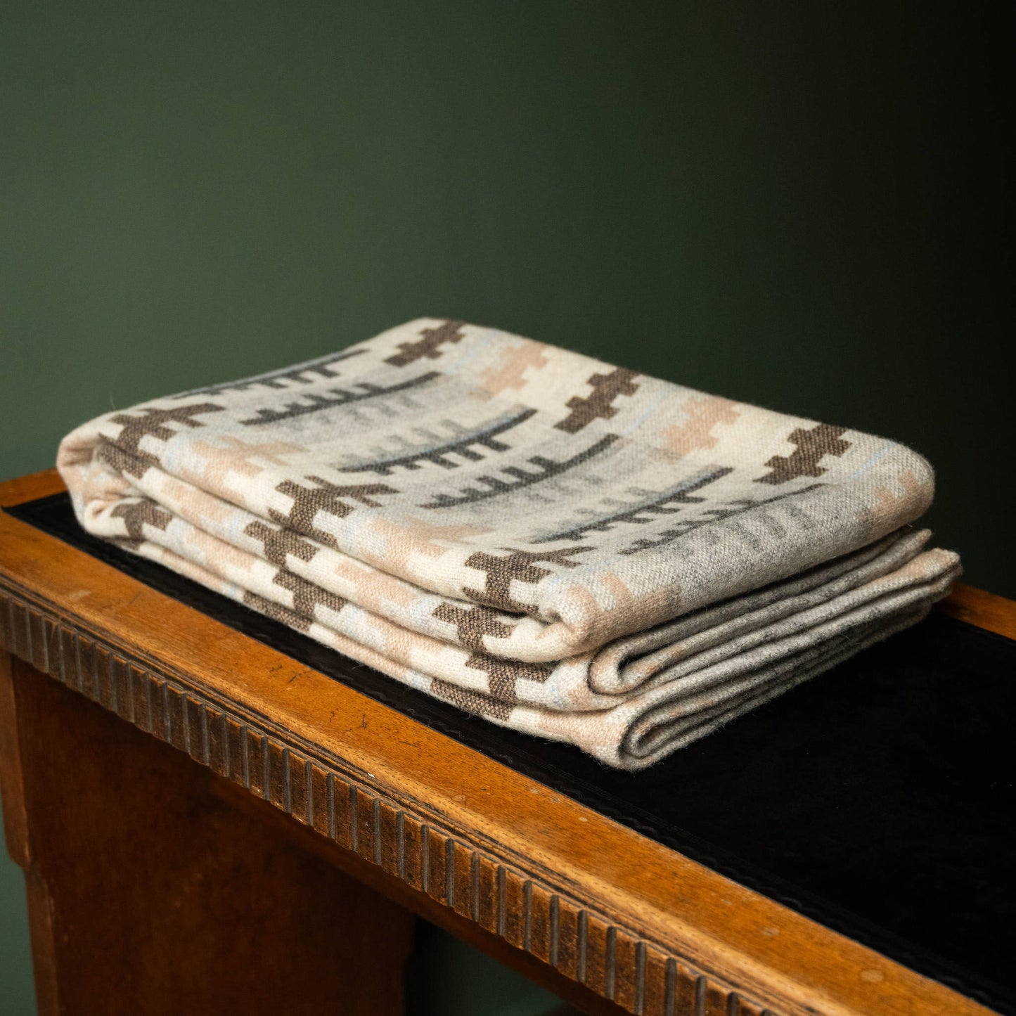 Melin Tregwynt traditional double cloth Welsh Blanket in Forest design. Folded on table.