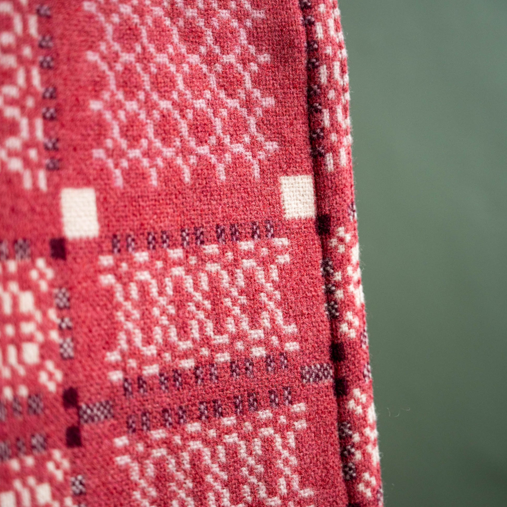 Close up of Melin Tregwynt Welsh Blanket, Knot Garden design in Mafon colour. 