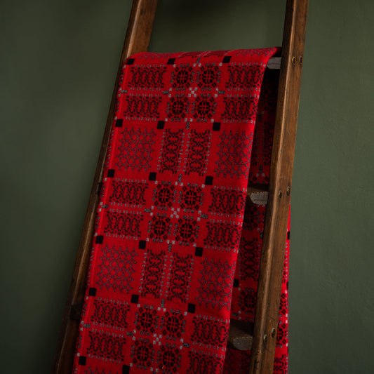 Melin Tregwynt Draig Welsh Blanket draped over a wooden ladder against a green wall