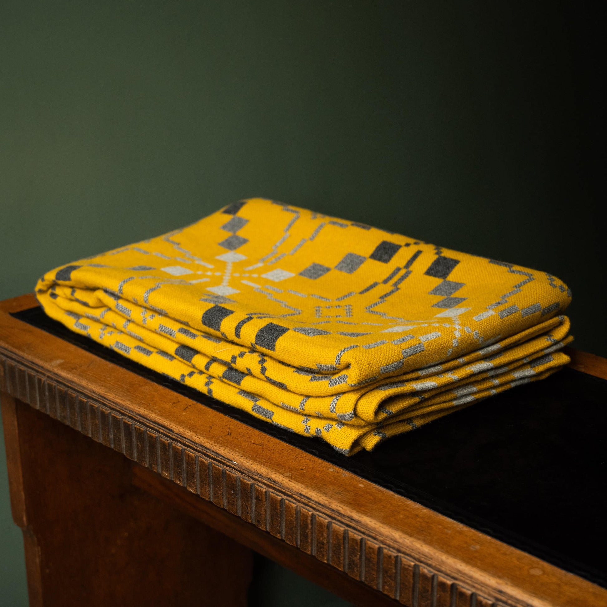 Melin Tregwynt Vintage Star  Welsh Blanket in Gorse colourway folded on desk. 