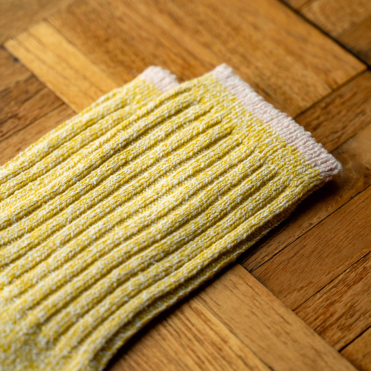 A close-up of Nishiguchi Kutsushita  yellow silk and cotton ribbed socks  showing the contrast colour cuff detail.