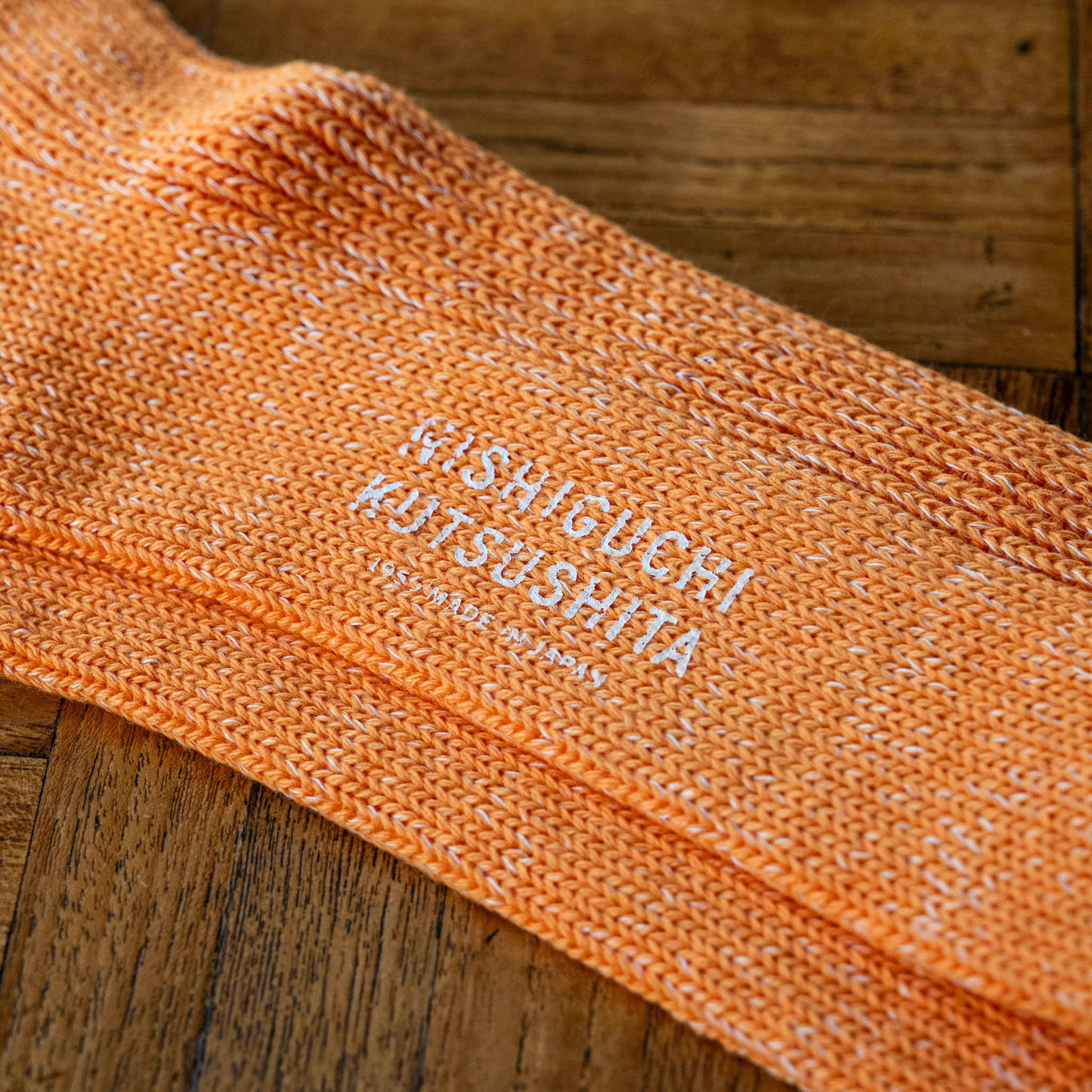 Lantern orange cotton & hemp sock with 'Nishiguchi Kutsushita' branding on the sole