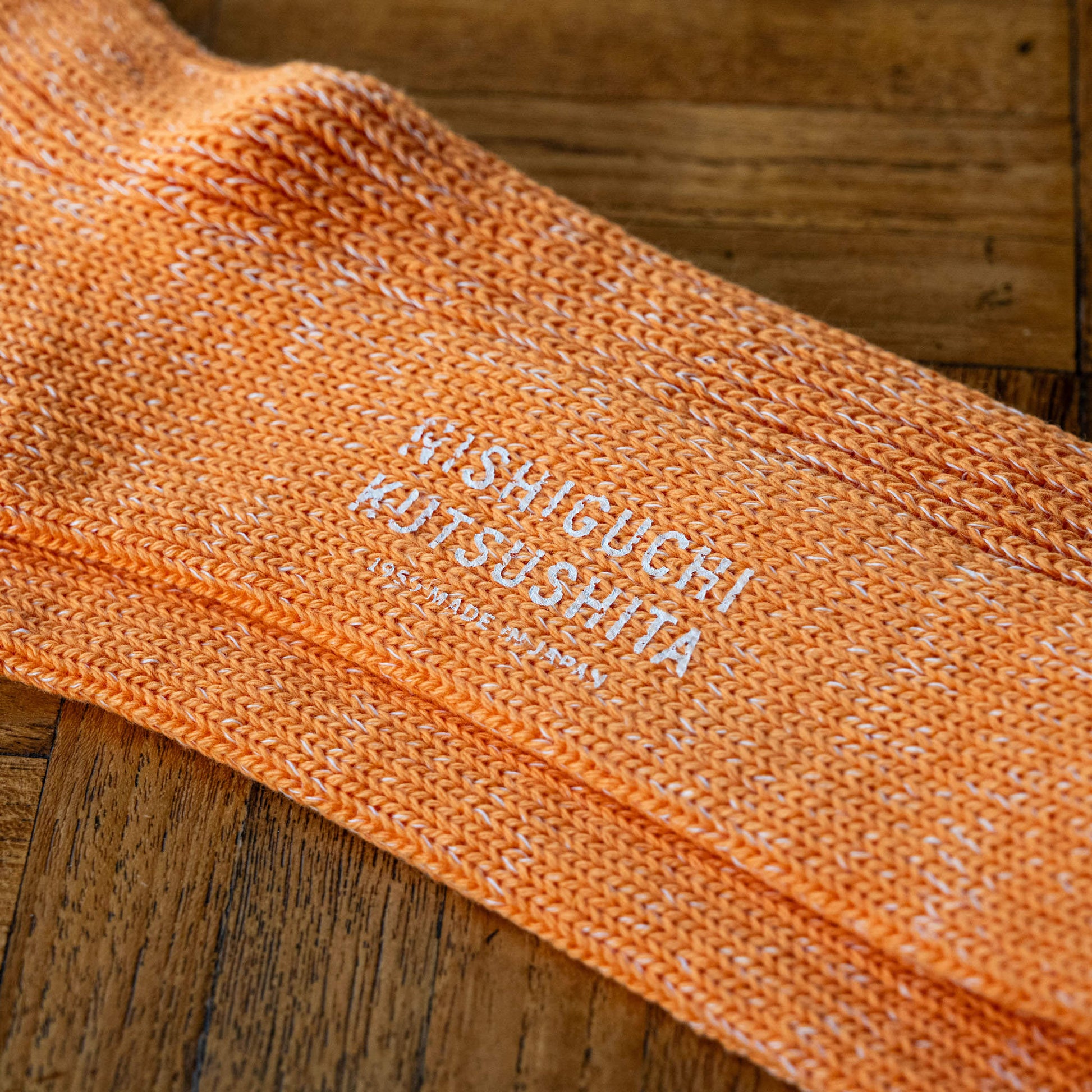 Lantern orange cotton & hemp sock with 'Nishiguchi Kutsushita' branding on the sole