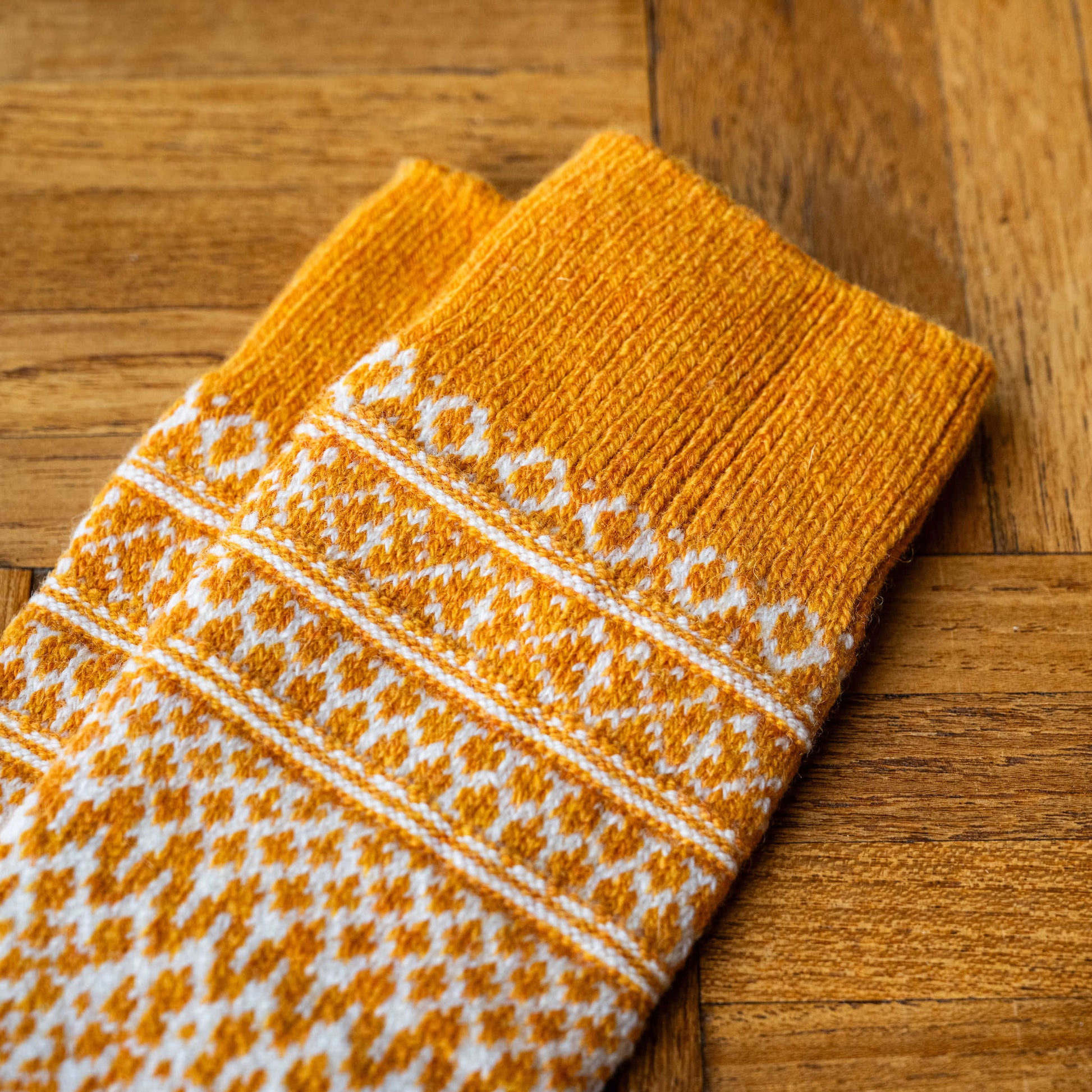 Cuff of Nishiguchi Kutsdushita wool jacquard socks in lantern orange with white geometric design  