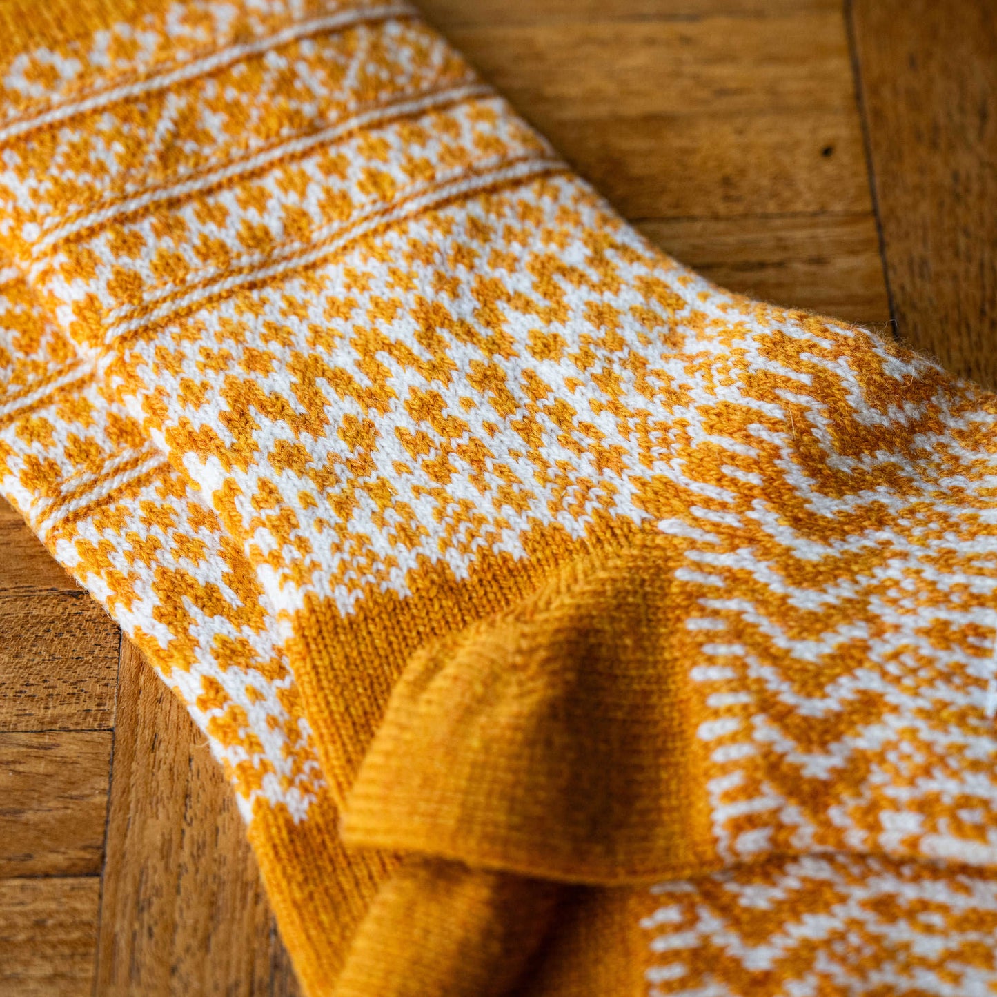 Heel of Nishiguchi Kutsushita wool jacquard socks in lantern orange with white geometric design  