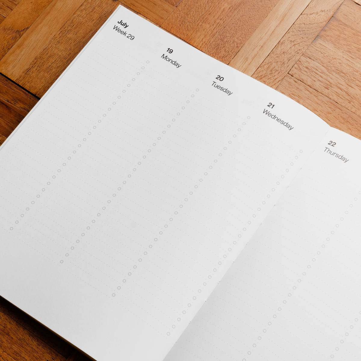 A close-up of an open weekly planner page from Pith Supply Pomelo Planner. The page is white with columns for each week day Monday through Sunday Headed by the month with days and dates.  