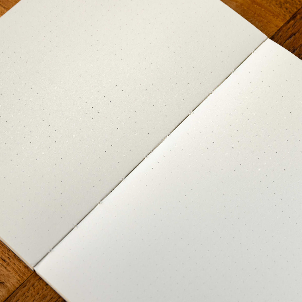 A close-up of Yuzu notebook page in off-white paper with a subtle dot grid layout, placed on a wooden surface.