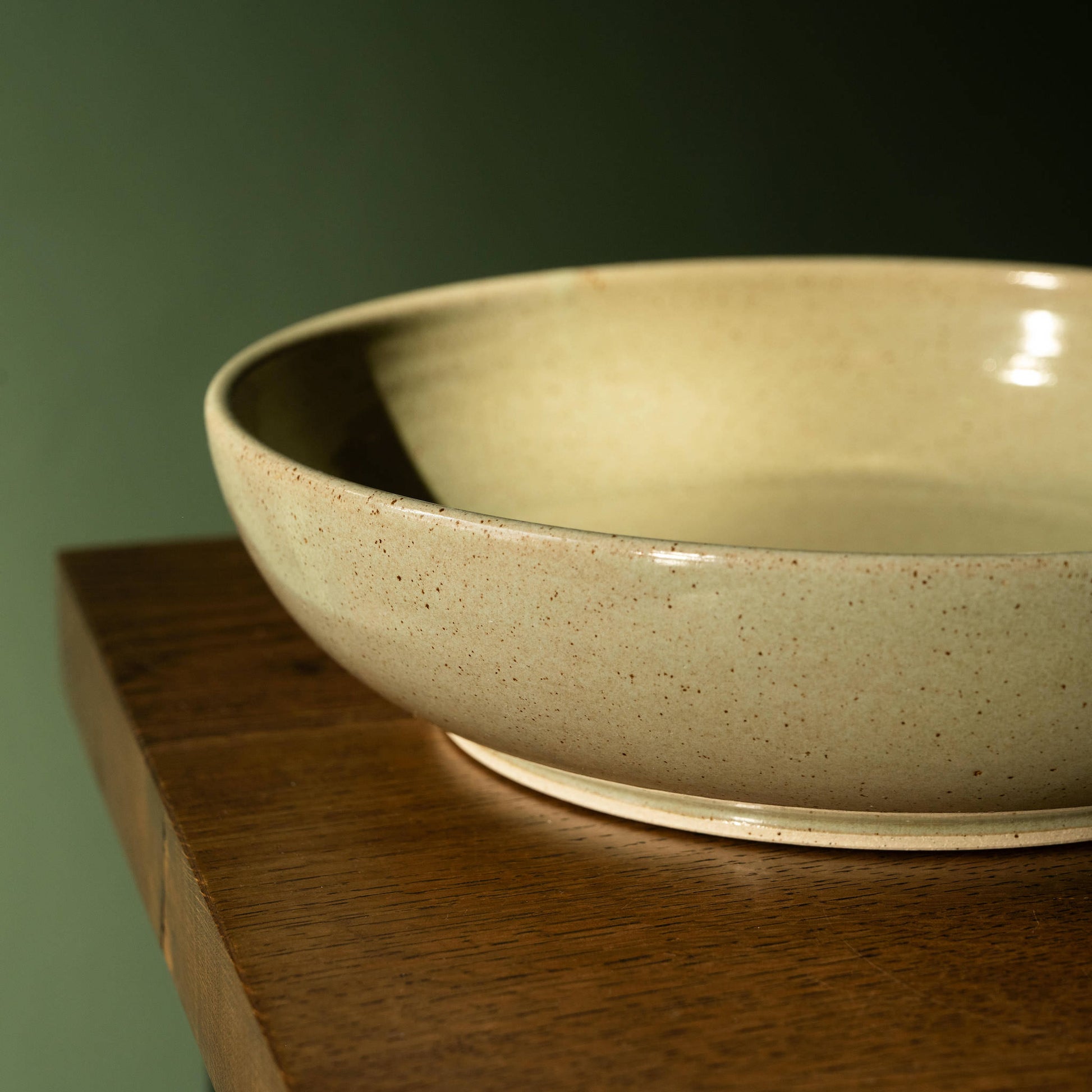 Pottery West Olive Flecked Stoneware Serving Bowl side view.