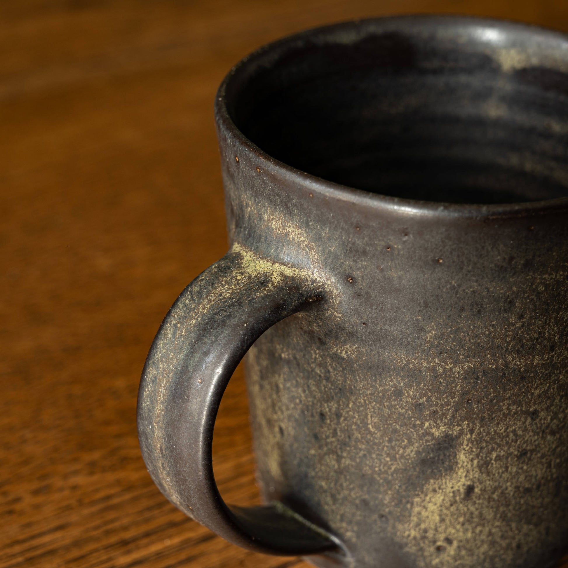 Handle of Pottery West Stoneware Tapered Mug in Charcoal Glaze.
