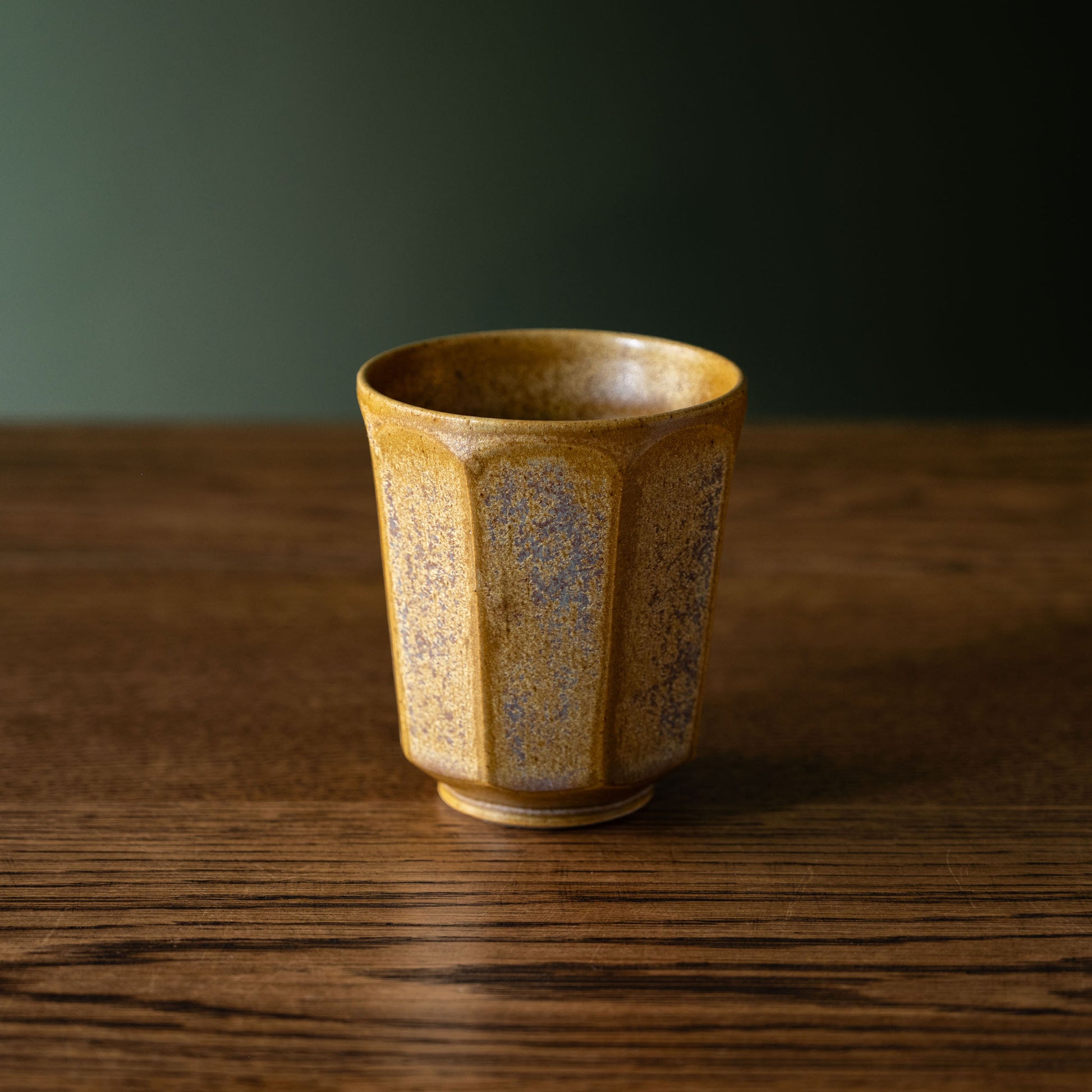 Pottery West ochre ceramic beaker on a wooden surface 