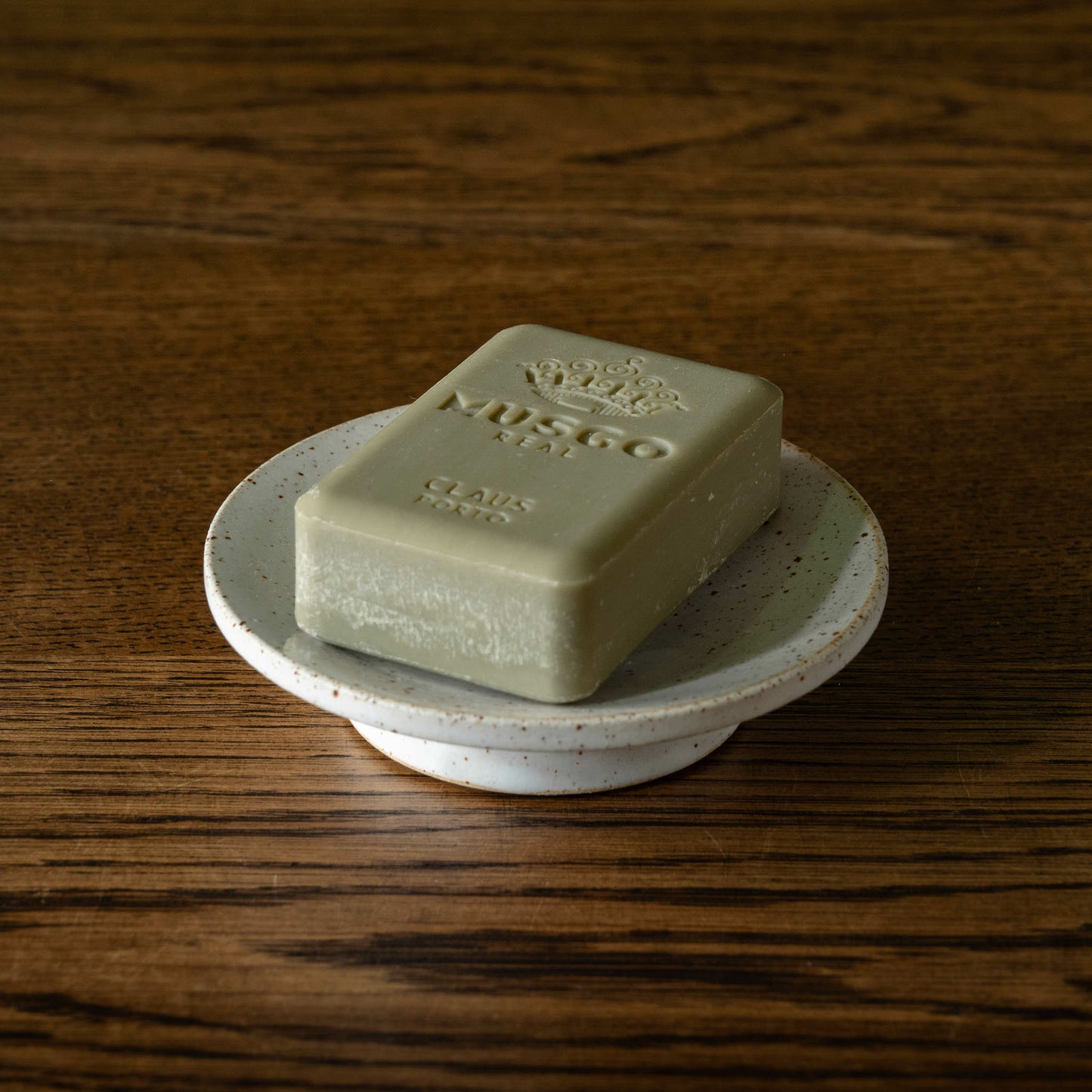 Pottery West circular stoneware speckled white soap dish with a bar of Musgo Real soap