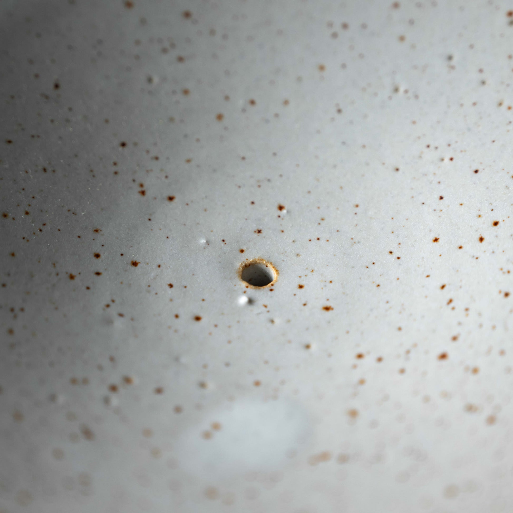 Pottery West speckled white stoneware soap dish close up of the drainage hole