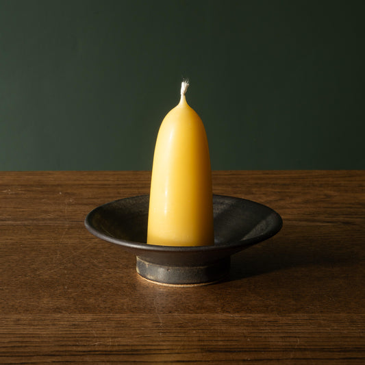 Pottery West stoneware stumpie candle holder in charcoal glaze with beeswax candle. 