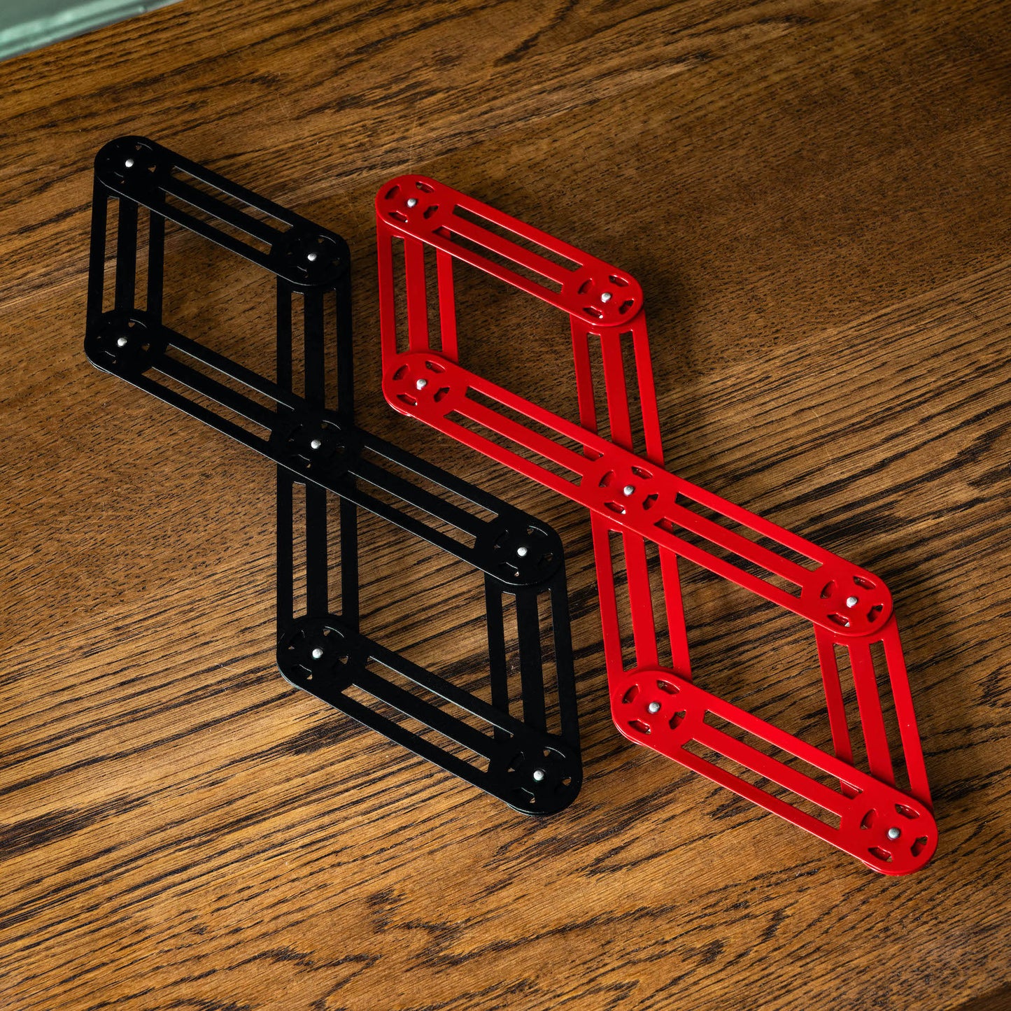 Stainless steel trivets in red & black, fully extended.