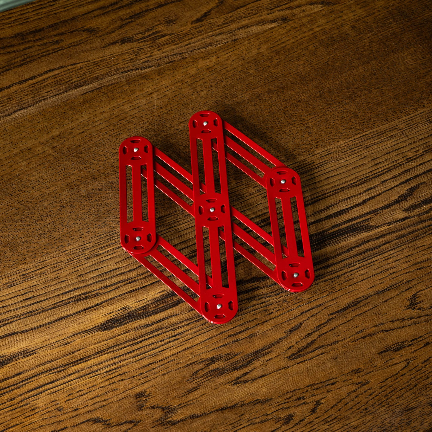 Stainless steel trivet in red, partially extended 