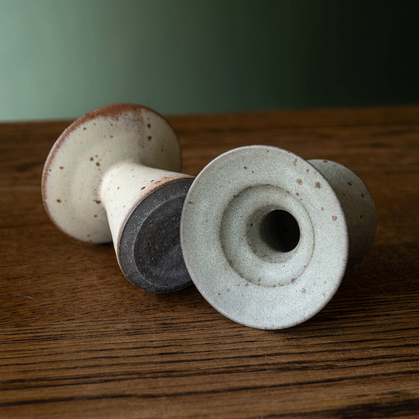 Two ceramic candleholders by Studio Brae with speckled cream and grey glazes, displaying the top and base.