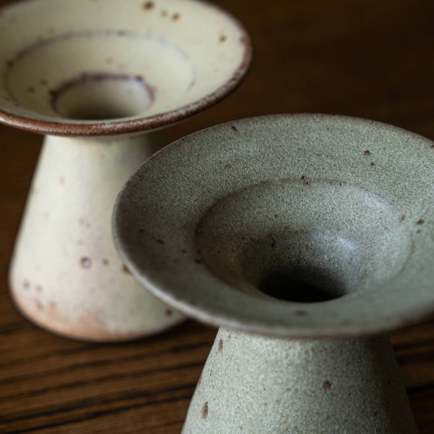 Two handmade ceramic candleholders by Studio Brae with a speckled glaze, showing the top of each holder where either the dinner or conical candle would rest.