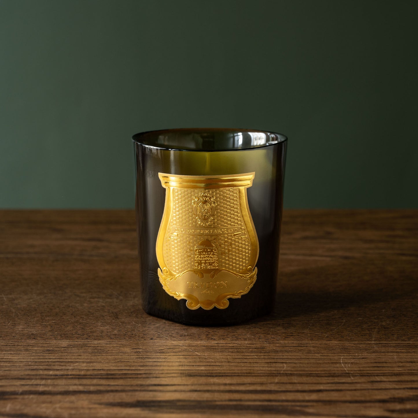 Trudon Cyrnos scented candle in dark green glass vessel with gold embossed design 