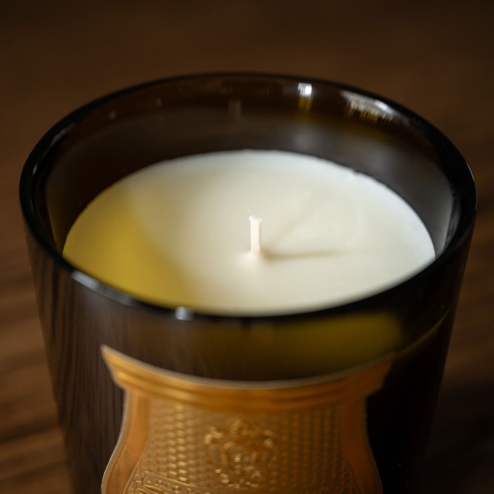Trudon Cyrnos Scented Candle with white candle wax and cotton wick in a dark green glass vessel 