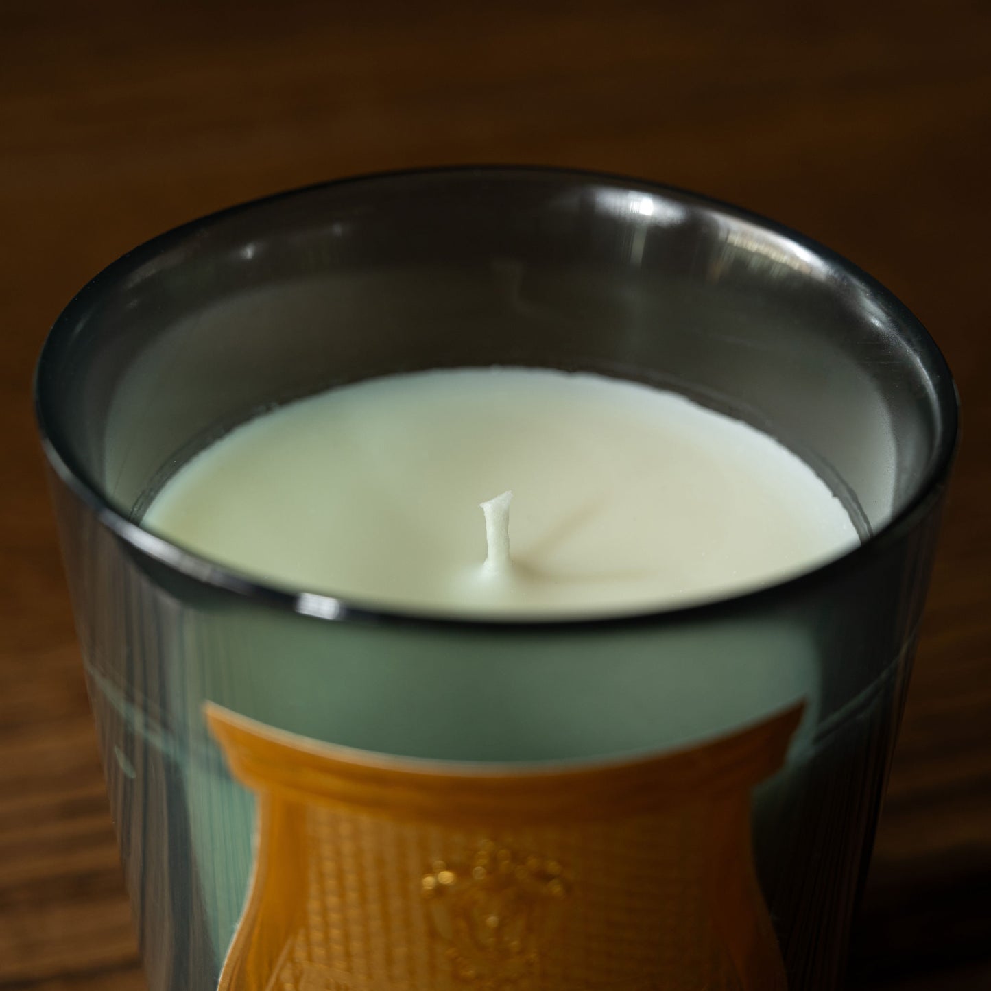 Trudon Figuerie Candle Wick in a celadon glass container with a decorative label on a wooden surface