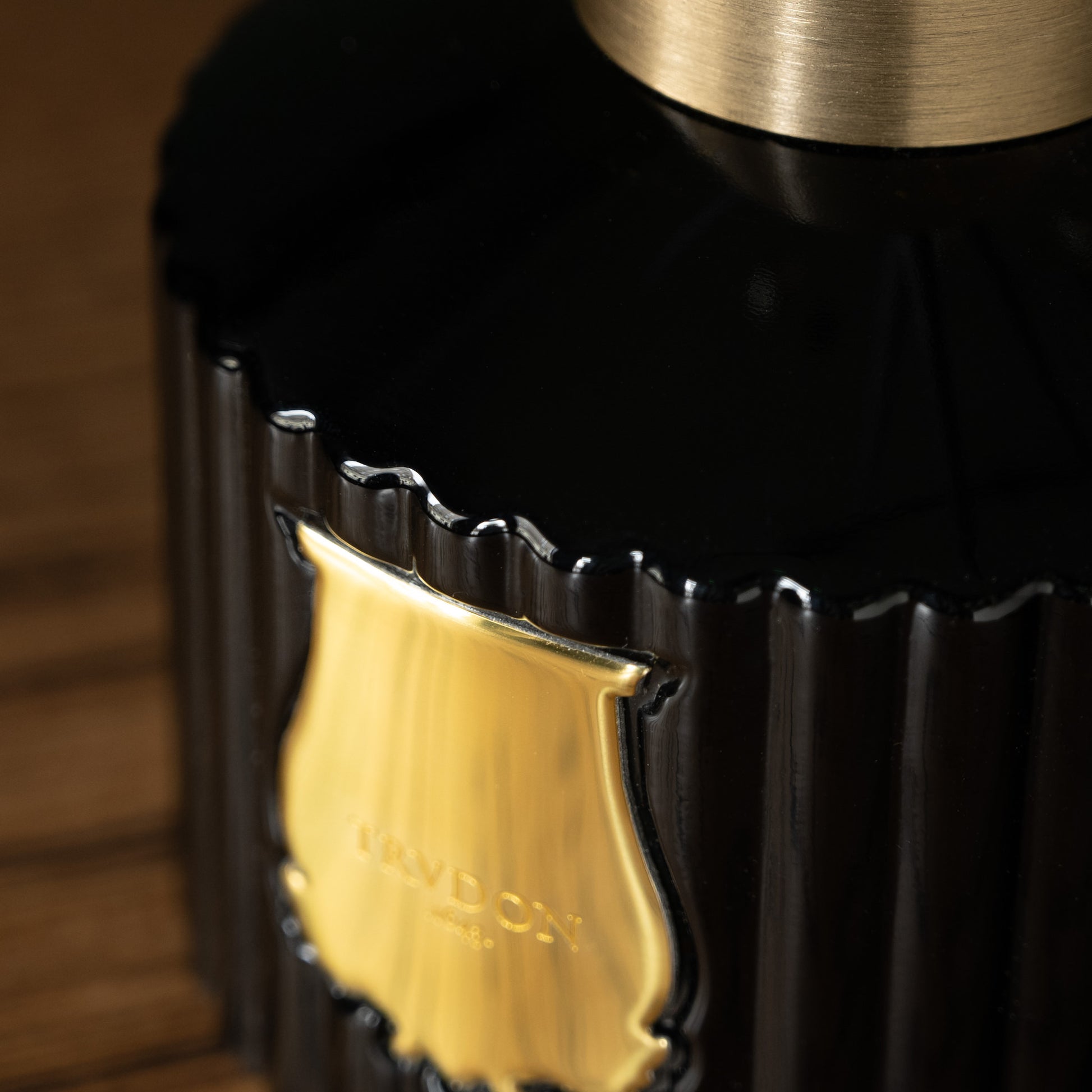 Close-up of Trudon Gabriel Reed Diffuser  dark green glass bottle with a gold logo 