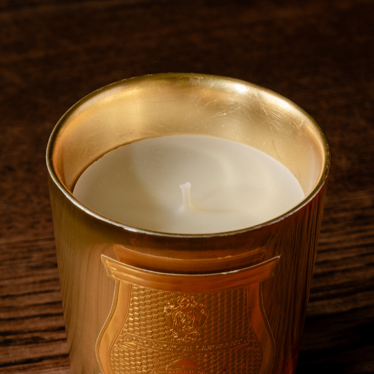 A close-up of Trudon limited edition La Nuit des Glaces Galerie des Flammes 270g scented candle. Housed in a gold mirror finish glass jar with a white wax candle.