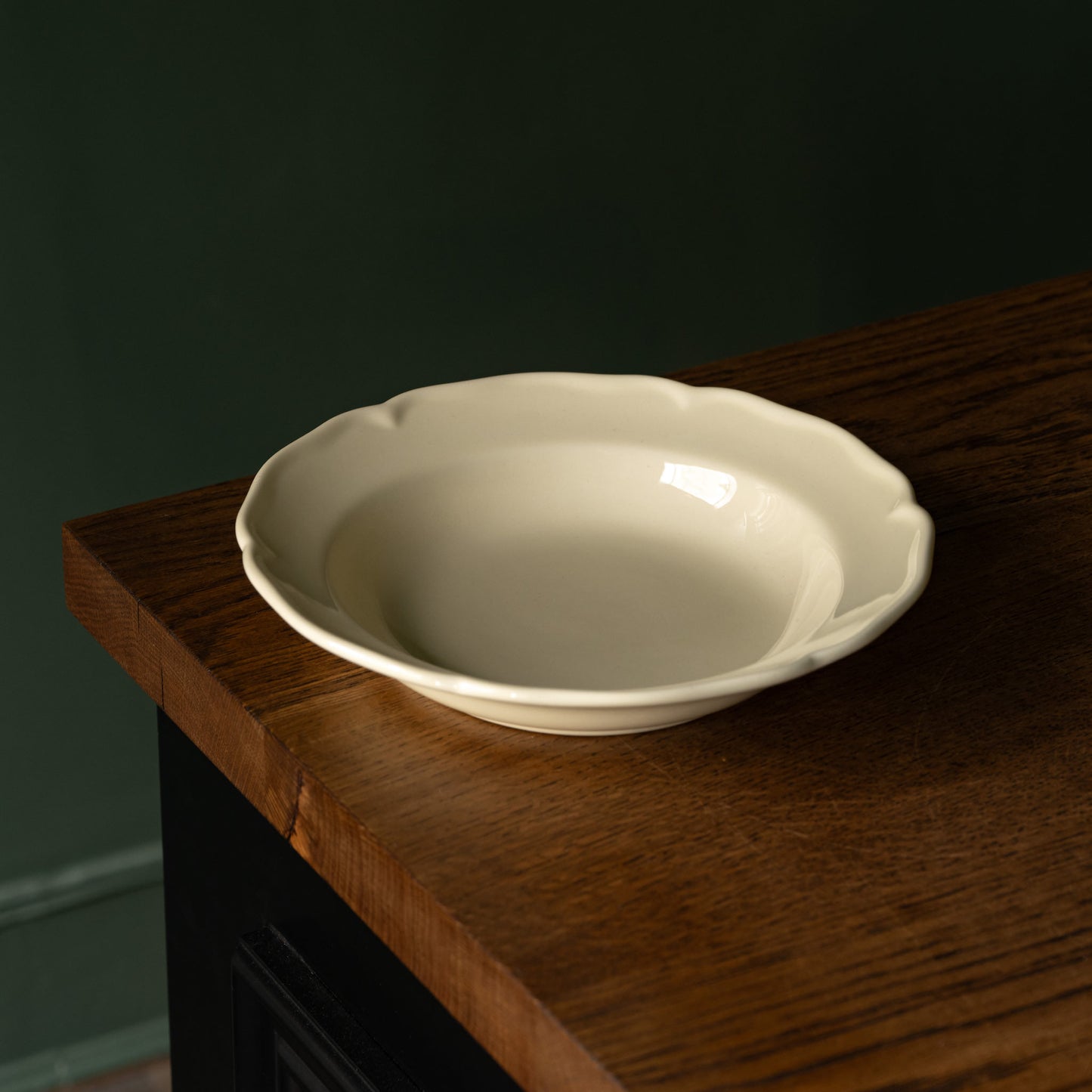 Glossy cream pottery dinner bowl with a scalloped rim design 