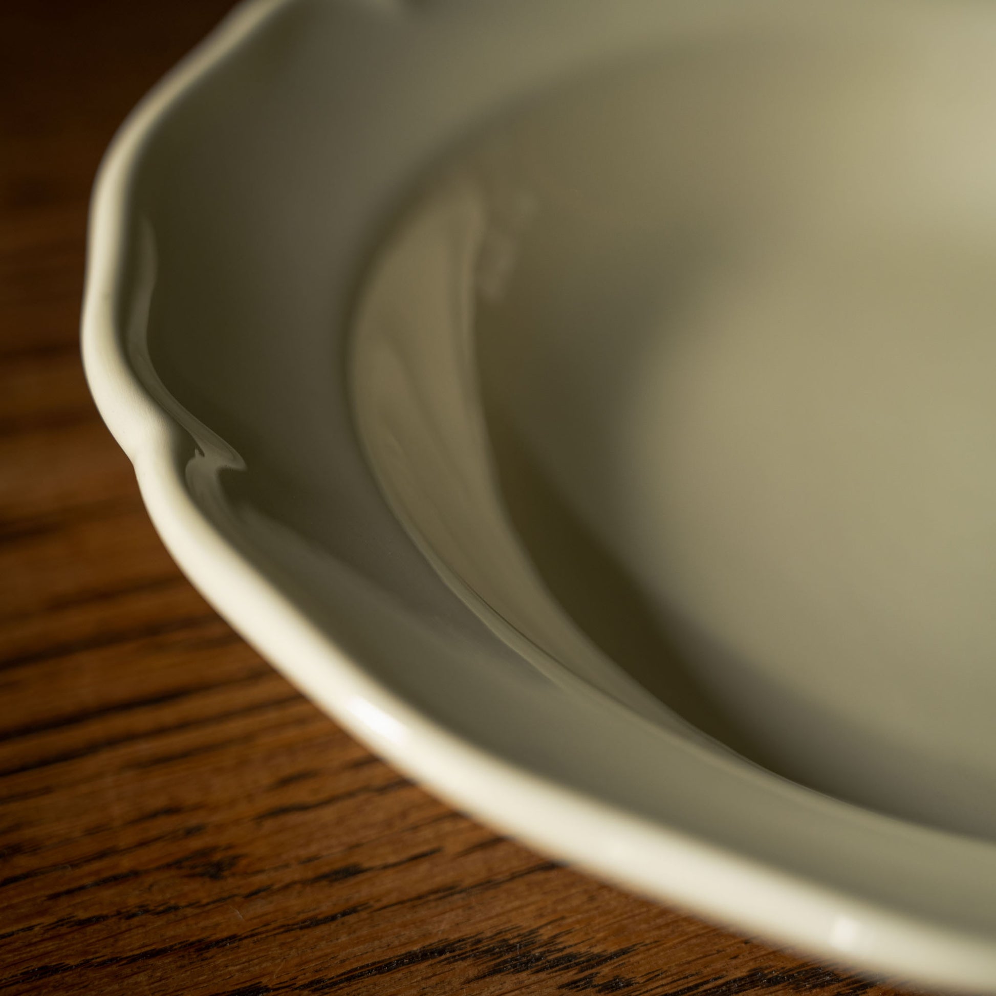 Close up of glossy cream pottery dinner bowl scalloped rim design 