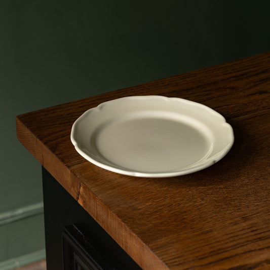 Glossy cream pottery side plate with scalloped rim design