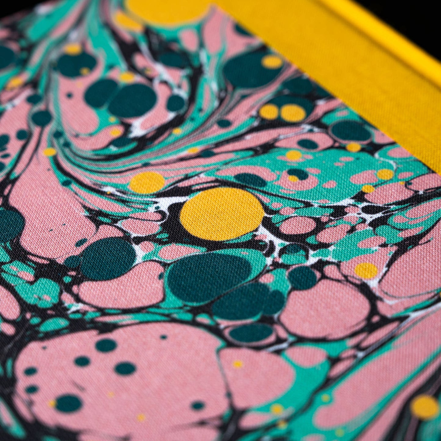 Close-up of a colourful marbled pattern notebookj with pink, green, and yellow colours.
